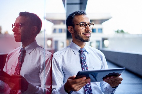 Businessman leaning on wall with tablet